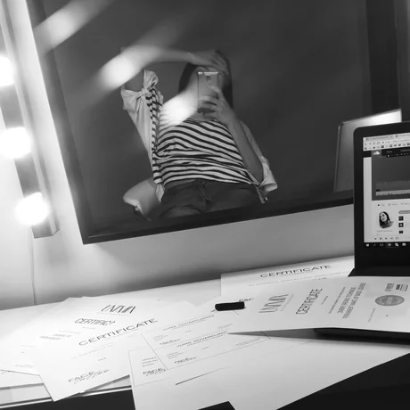 UNIMIX darbo vieta: veidrodis su kompiuterio ekranu, ant stalo išdėlioti mokymų sertifikatai